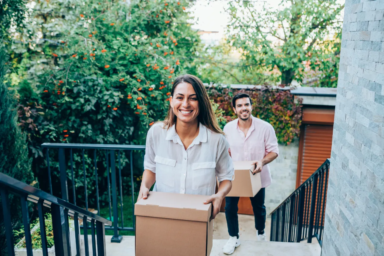 Couple smiling carrying moving boxes